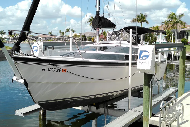 Slide: The Image of 2011 MacGregor 26M sailboat docked on a lift in a sunny marina. - 3