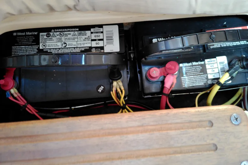 Slide: The Image of Batteries in a 2011 MacGregor 26M boat, featuring West Marine labels and wiring connections. - 30