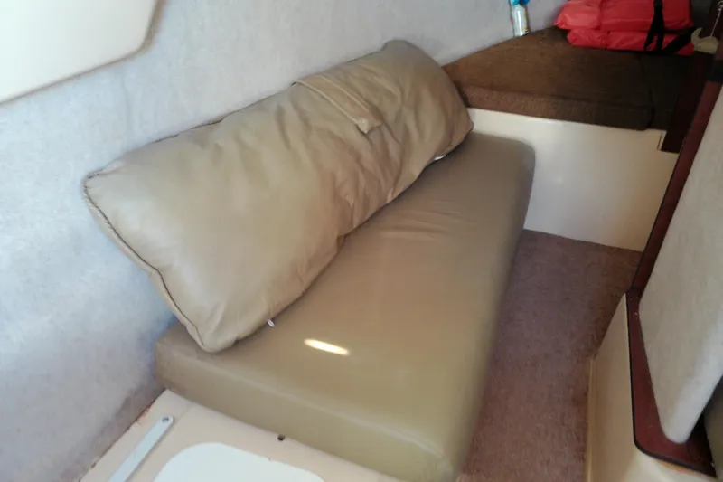Slide: The Image of Interior cabin of 2011 MacGregor 26M sailboat with beige cushions and storage space. - 32