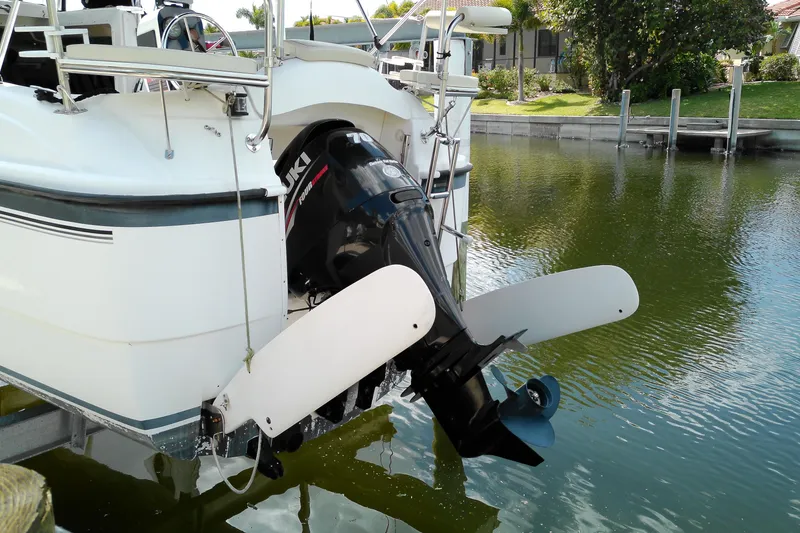 Slide: The Image of 2011 MacGregor 26M sailboat with Suzuki outboard motor in a calm marina. - 5