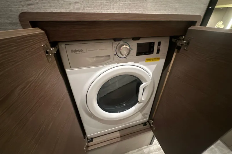 Slide: The Image of Built-in washer in 2026 Cruisers Yachts 50 Fly, behind wooden cabinet doors. - 23