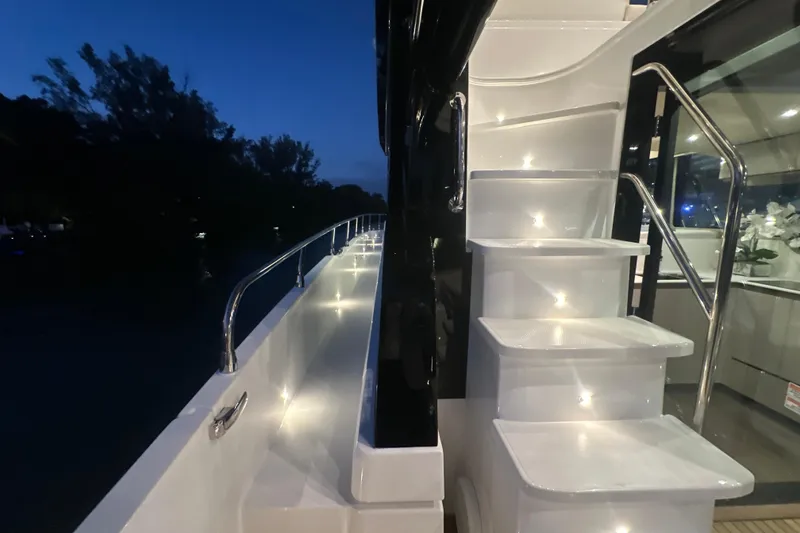 Slide: The Image of 2026 Cruisers Yachts 50 Fly illuminated stairs and deck at dusk. - 40