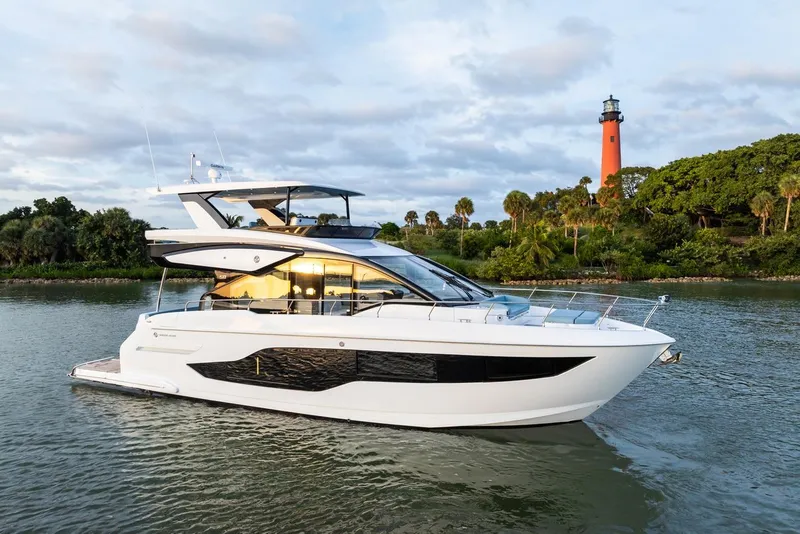 Slide: The Image of 2026 Cruisers Yachts 50 Fly on water near lighthouse, scenic background. - 54