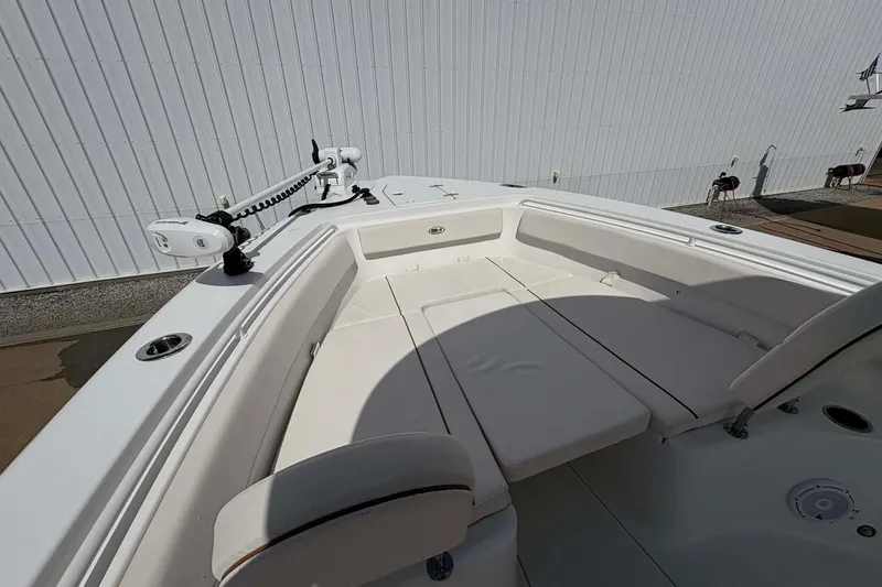 Slide: The Image of 2021 Sea Hunt boat with white seating and trolling motor, docked near a white building. - 12