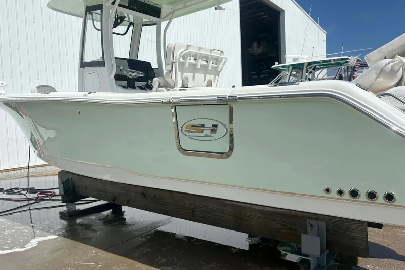 Slide: The Image of 2021 Sea Hunt boat on a lift, white hull, outdoor storage facility. - 2