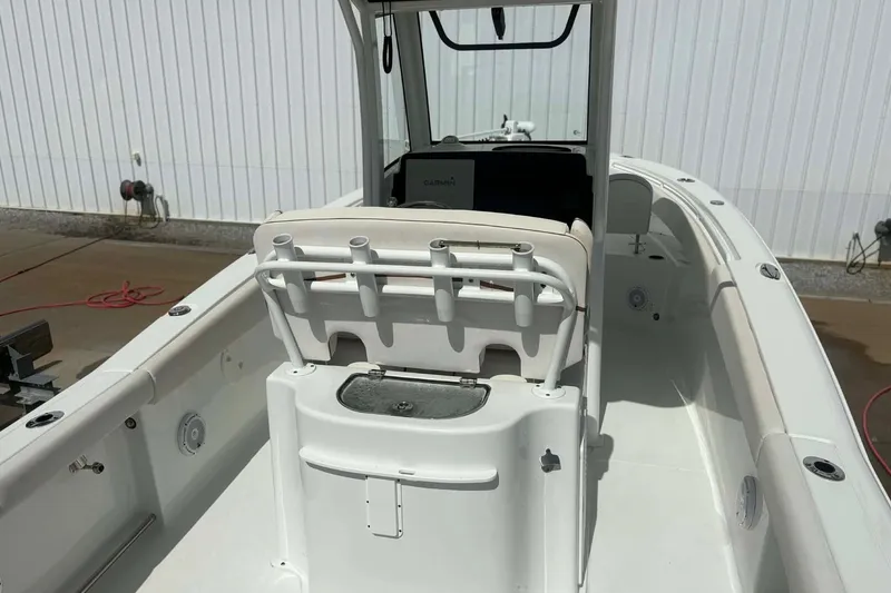 Slide: The Image of 2021 Sea Hunt boat interior with rod holders and console, docked near a white wall. - 8