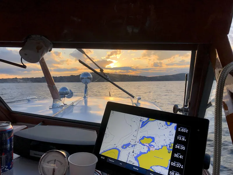 Slide: The Image of 1956 Chris-Craft Captain boat interior with navigation screen, sunset view over water. - 8