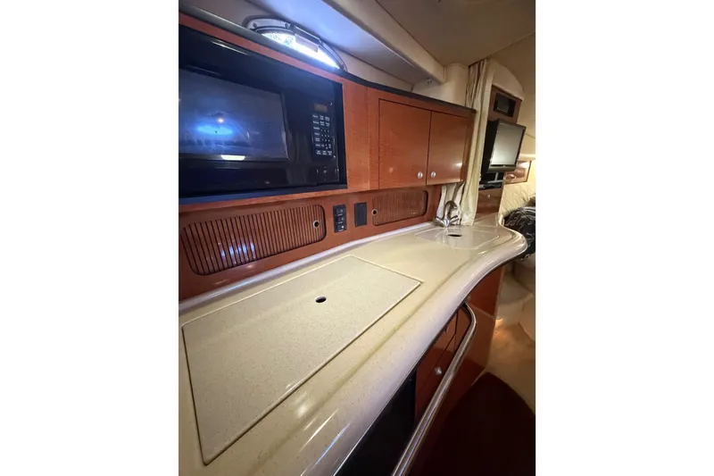 Slide: The Image of 2005 Sea Ray Sundancer 320 interior kitchen with microwave, sink, and wooden cabinetry. - 13