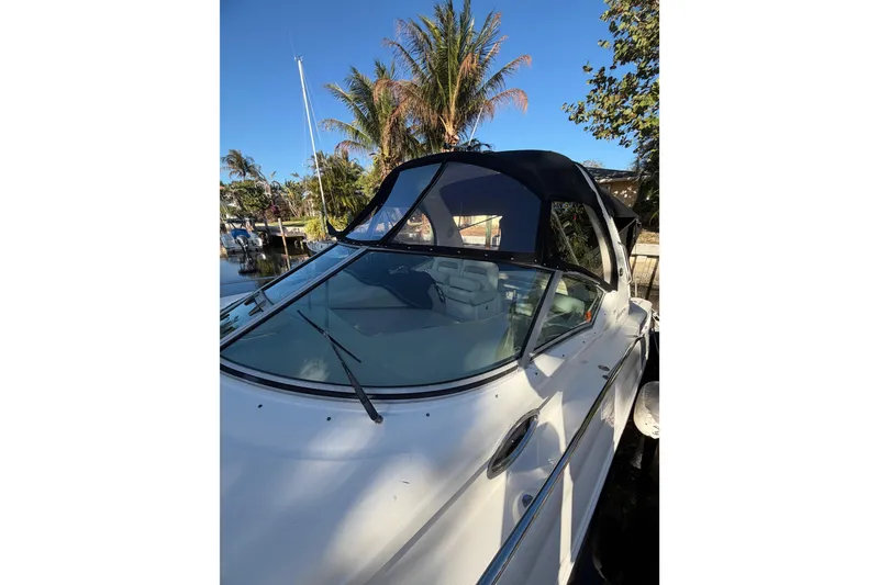 Slide: The Image of 2005 Sea Ray Sundancer 320 boat docked, featuring sleek design and canopy, with palm trees in background. - 8