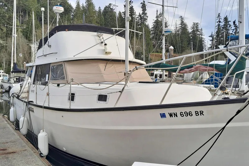 The Image of 1979 Mainship 34 Sedan docked at marina, surrounded by trees and other boats. - 0