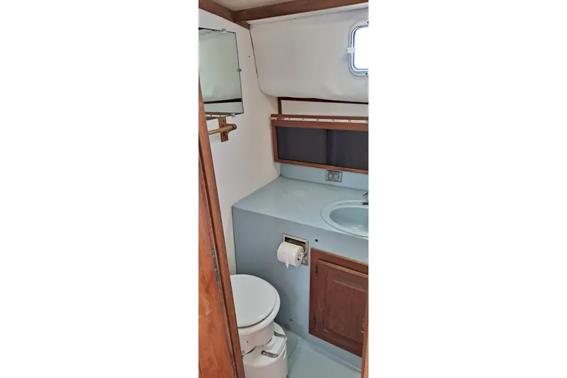 Slide: The Image of 1979 Mainship 34 Sedan bathroom with sink, toilet, and wooden cabinetry. - 10