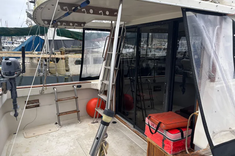 Slide: The Image of 1979 Mainship 34 Sedan boat deck with ladder, life jackets, and marina view. - 14