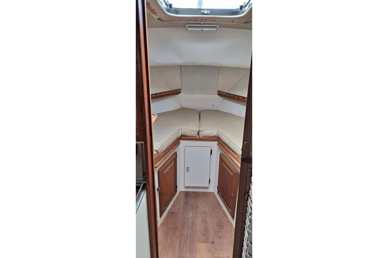 Slide: The Image of 1979 Mainship 34 Sedan cabin interior with wood accents and beige cushions. - 9