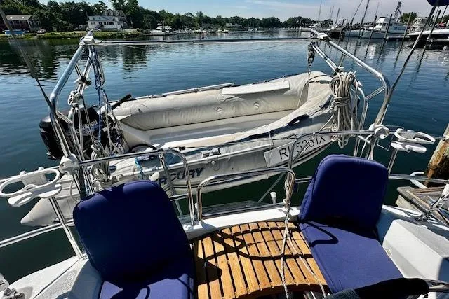 Slide: The Image of 1986 Hunter Passage 450 sailboat with dinghy, docked in a serene marina setting. - 2