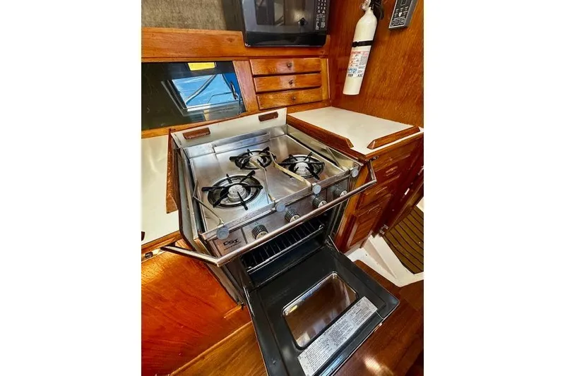Slide: The Image of 1986 Hunter Passage 450 yacht kitchen with stove, oven, and microwave in wooden cabinetry. - 29