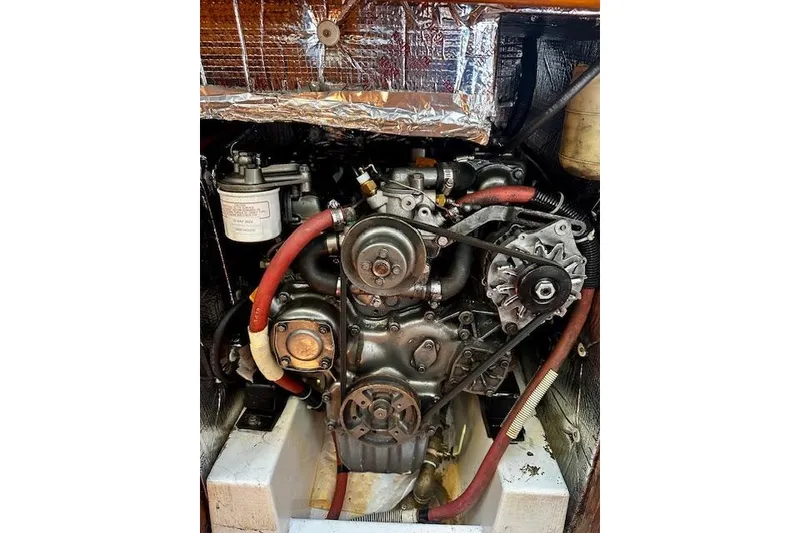 Slide: The Image of Engine of 1986 Hunter Passage 450 sailboat, featuring red hoses and metallic components. - 39