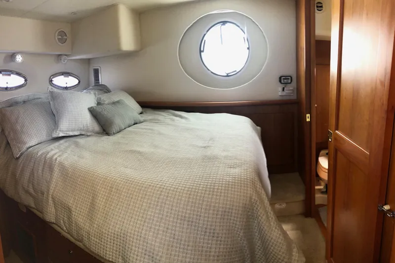 Slide: The Image of 2003 Silverton 35 Motor Yacht bedroom with cozy bedding and porthole window. - 11