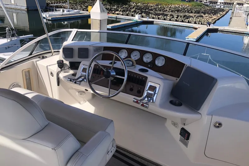 Slide: The Image of 2003 Silverton 35 Motor Yacht helm with steering wheel and control panel, docked at marina. - 13
