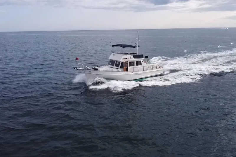 The Image of 1990 Grand Banks 46 Classic yacht cruising on open sea under cloudy skies. - 1