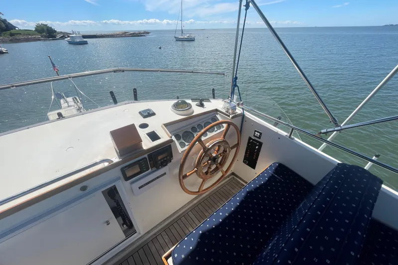 Slide: The Image of 1990 Grand Banks 46 Classic yacht helm with wooden wheel, overlooking serene waters. - 6