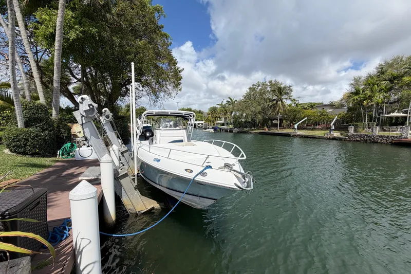 Slide: The Image of 2008 Donzi 29 ZF Cuddy boat docked by a scenic waterfront with lush greenery. - 3