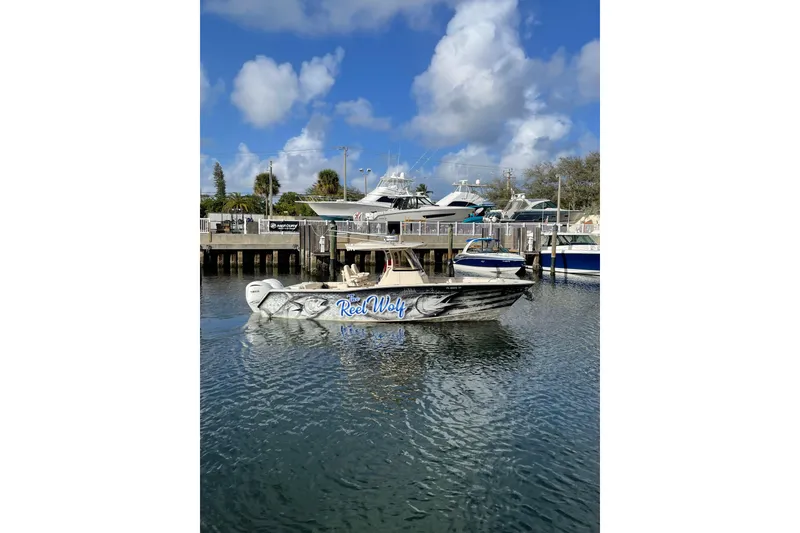 Slide: The Image of 2023 Grady-White Canyon 306 boat docked, featuring custom "Reel Wolf" design. - 4