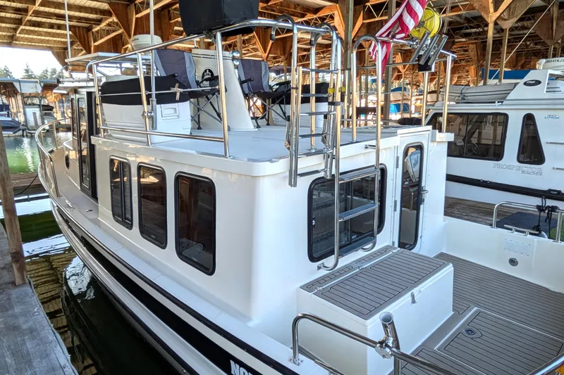 Slide: The Image of 2002 Nordic Tug 32 docked in a marina, showcasing its sleek design and spacious deck. - 11