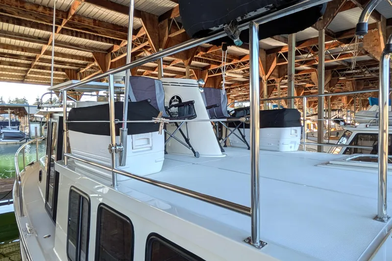 Slide: The Image of 2002 Nordic Tug 32 boat deck with chairs and storage under covered marina. - 12