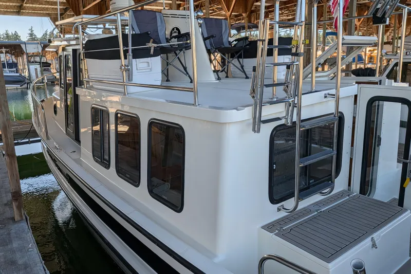 Slide: The Image of 2002 Nordic Tug 32 docked in a marina, showcasing its sleek design and upper deck seating. - 19