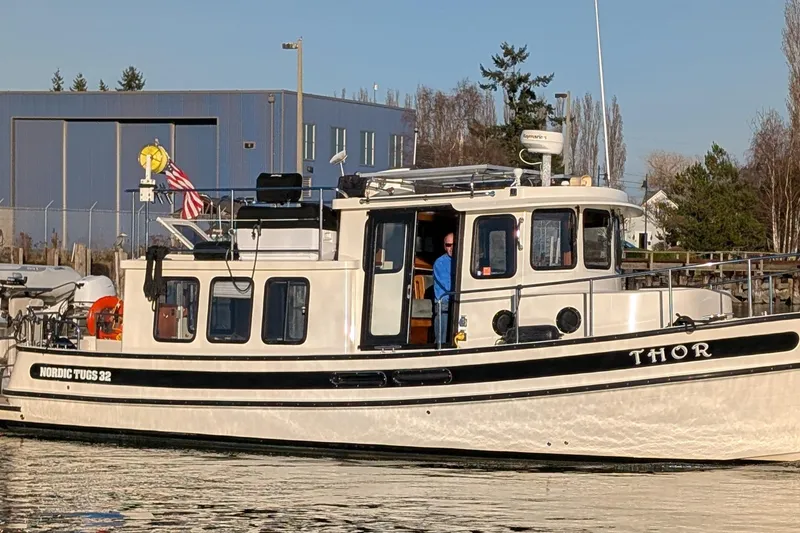 Slide: The Image of 2002 Nordic Tug 32 boat named "Thor" docked near industrial building. - 2