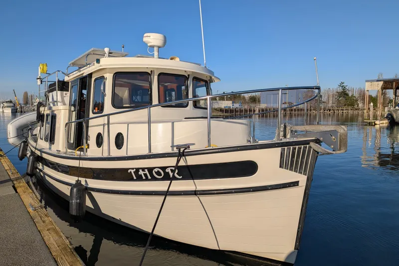 Slide: The Image of 2002 Nordic Tug 32 docked at marina under clear blue sky. - 26