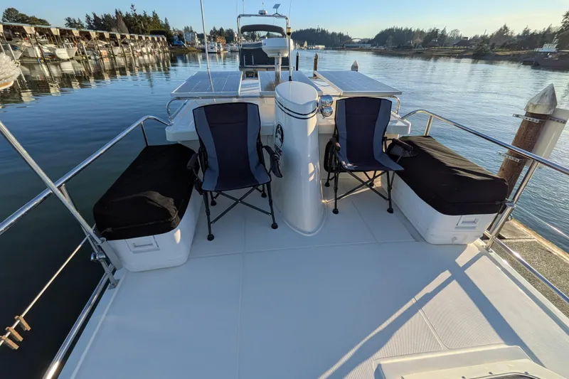 Slide: The Image of Deck of 2002 Nordic Tug 32 with chairs and storage, docked in a serene marina. - 27