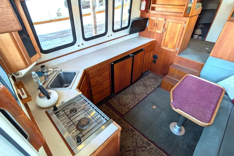 Slide: The Image of Interior of 2002 Nordic Tug 32 with kitchen, seating, and wooden cabinetry. - 32
