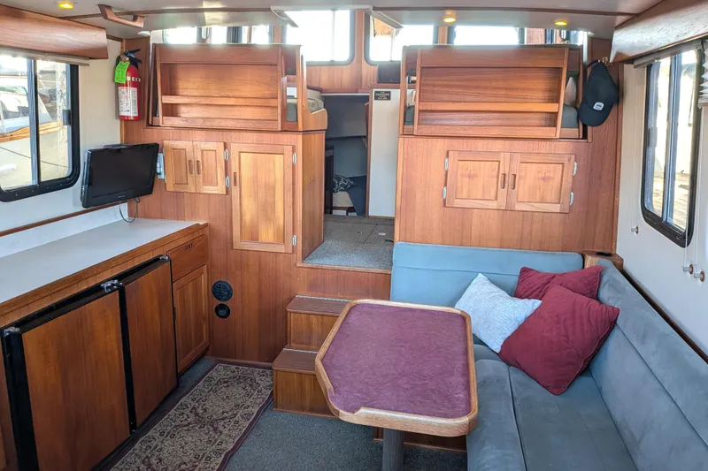 Slide: The Image of Interior of 2002 Nordic Tug 32, featuring cozy seating, wooden cabinetry, and a compact kitchen area. - 34