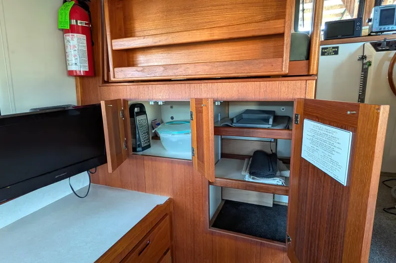 Slide: The Image of Interior of a 2002 Nordic Tug 32 with wooden cabinets and a small TV. - 35