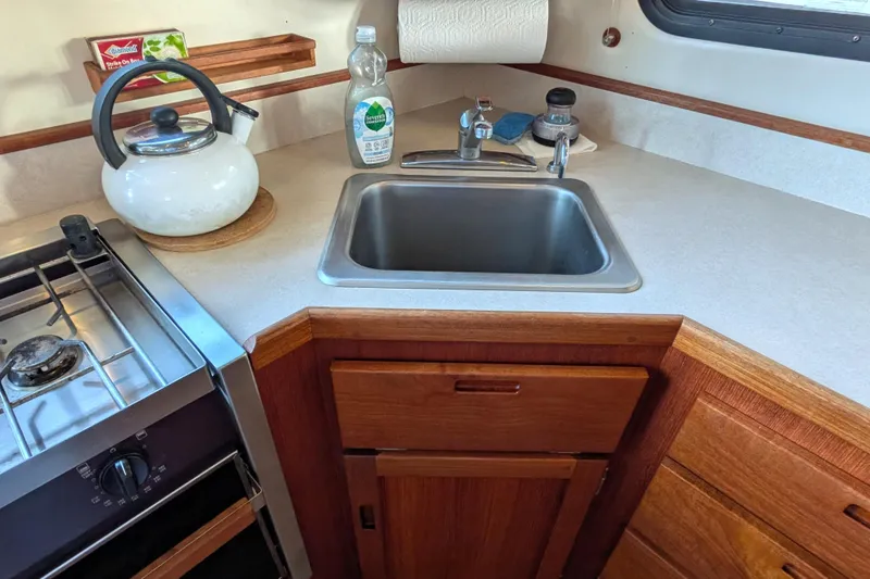 Slide: The Image of Compact kitchen in a 2002 Nordic Tug 32, featuring a sink, stove, and kettle. - 37
