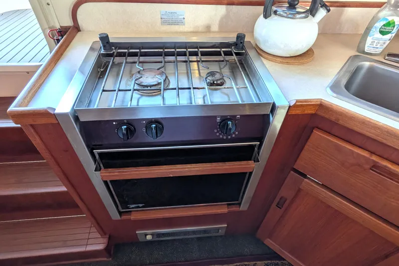 Slide: The Image of Stove and oven in 2002 Nordic Tug 32 boat kitchen, with wooden cabinetry. - 38