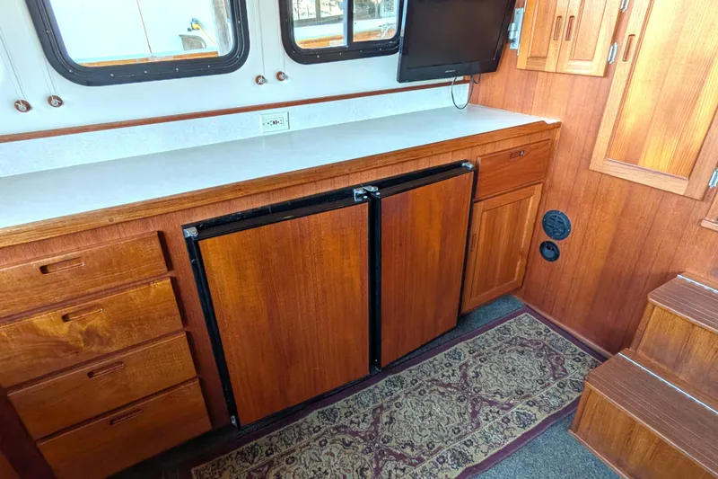 Slide: The Image of 2002 Nordic Tug 32 interior with wooden cabinetry, mini fridge, and mounted TV. - 39