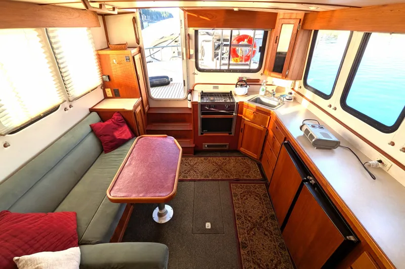 Slide: The Image of Interior of 2002 Nordic Tug 32, featuring cozy seating, kitchen, and large windows. - 40