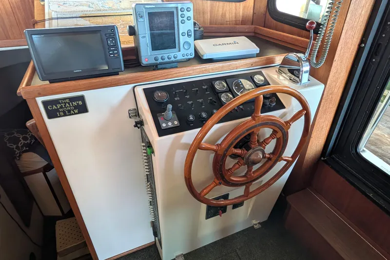 Slide: The Image of 2002 Nordic Tug 32 helm with wooden wheel, navigation equipment, and "The Captain's Word is Law" sign. - 49