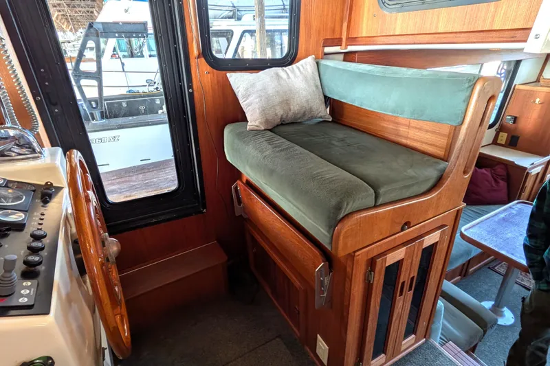 Slide: The Image of Interior of a 2002 Nordic Tug 32, featuring a cozy seating area and helm controls. - 54