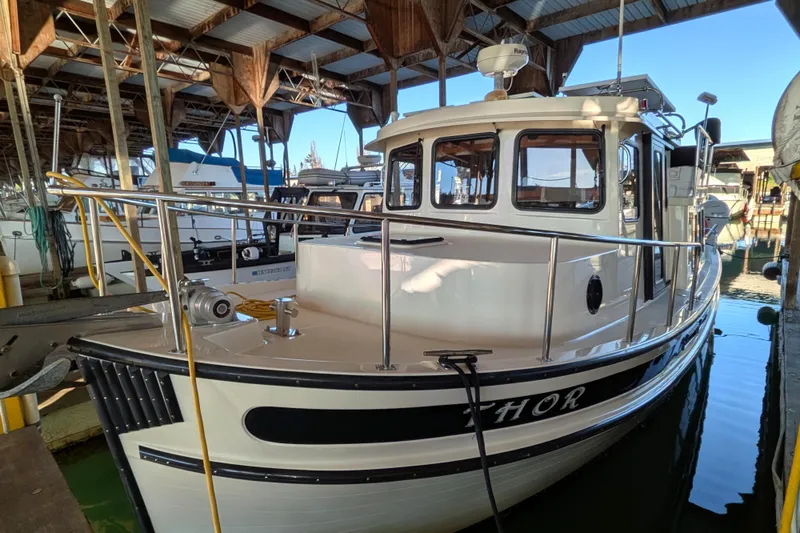 Slide: The Image of 2002 Nordic Tug 32 docked in a covered marina, showcasing its classic design. - 7