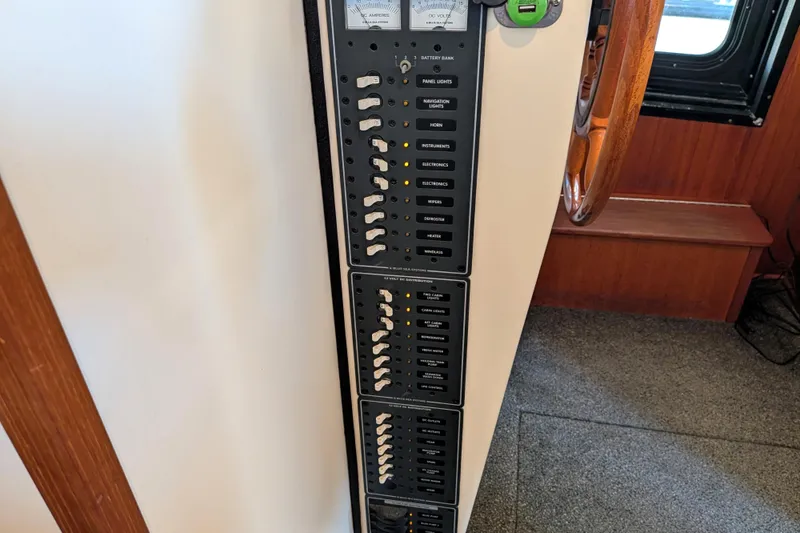 Slide: The Image of Control panel of a 2002 Nordic Tug 32 boat, featuring various switches and gauges. - 71