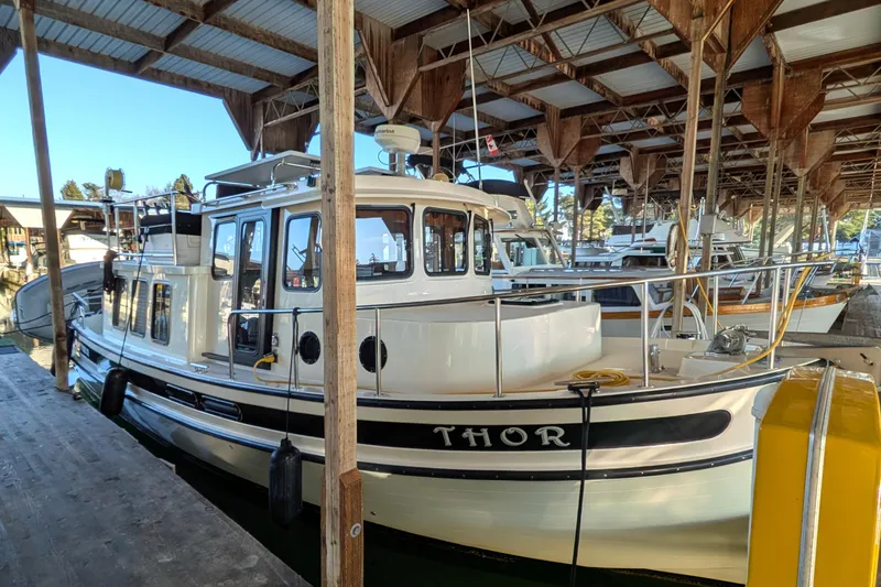 Slide: The Image of 2002 Nordic Tug 32 docked in a covered marina, named "Thor". - 8