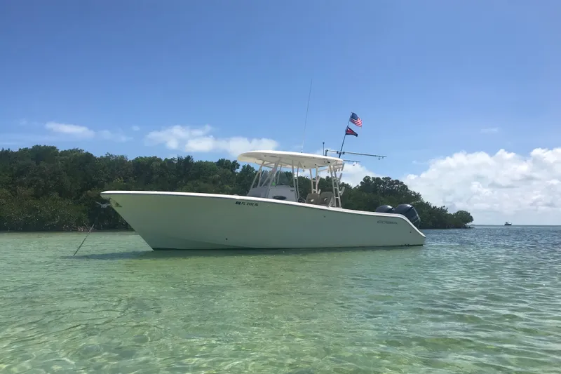 The Image of 2018 Cobia 301 Center Console boat anchored in clear water, with American flag. - 11