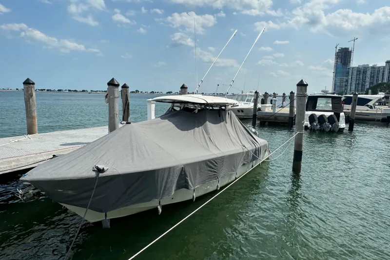 Slide: The Image of 2018 Cobia 301 Center Console boat covered at marina dock. - 13