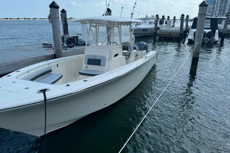 Slide: The Image of 2018 Cobia 301 Center Console boat docked at marina, calm water background. - 14