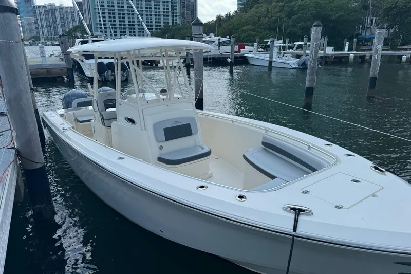 Slide: The Image of 2018 Cobia 301 Center Console boat docked in marina, surrounded by water and other vessels. - 15