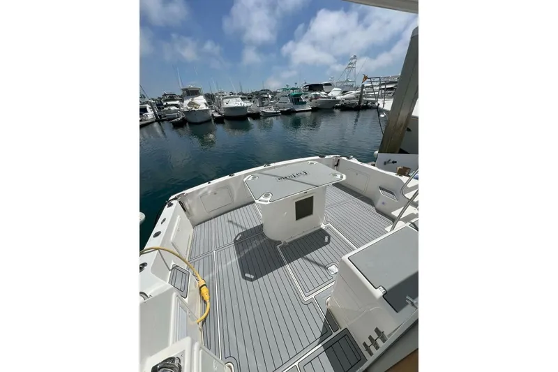 Slide: The Image of 2002 Riviera 43 Open Flybridge yacht docked at marina, featuring spacious deck and clear skies. - 4