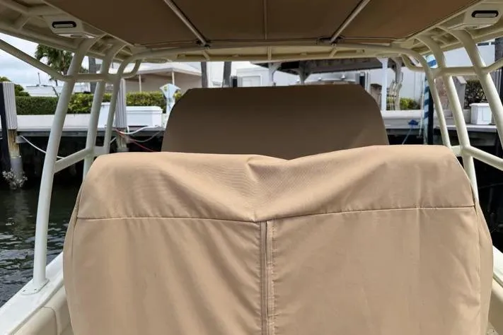 Slide: The Image of 2018 Chris-Craft Catalina 30 boat with beige seat covers and canopy, docked by the water. - 9